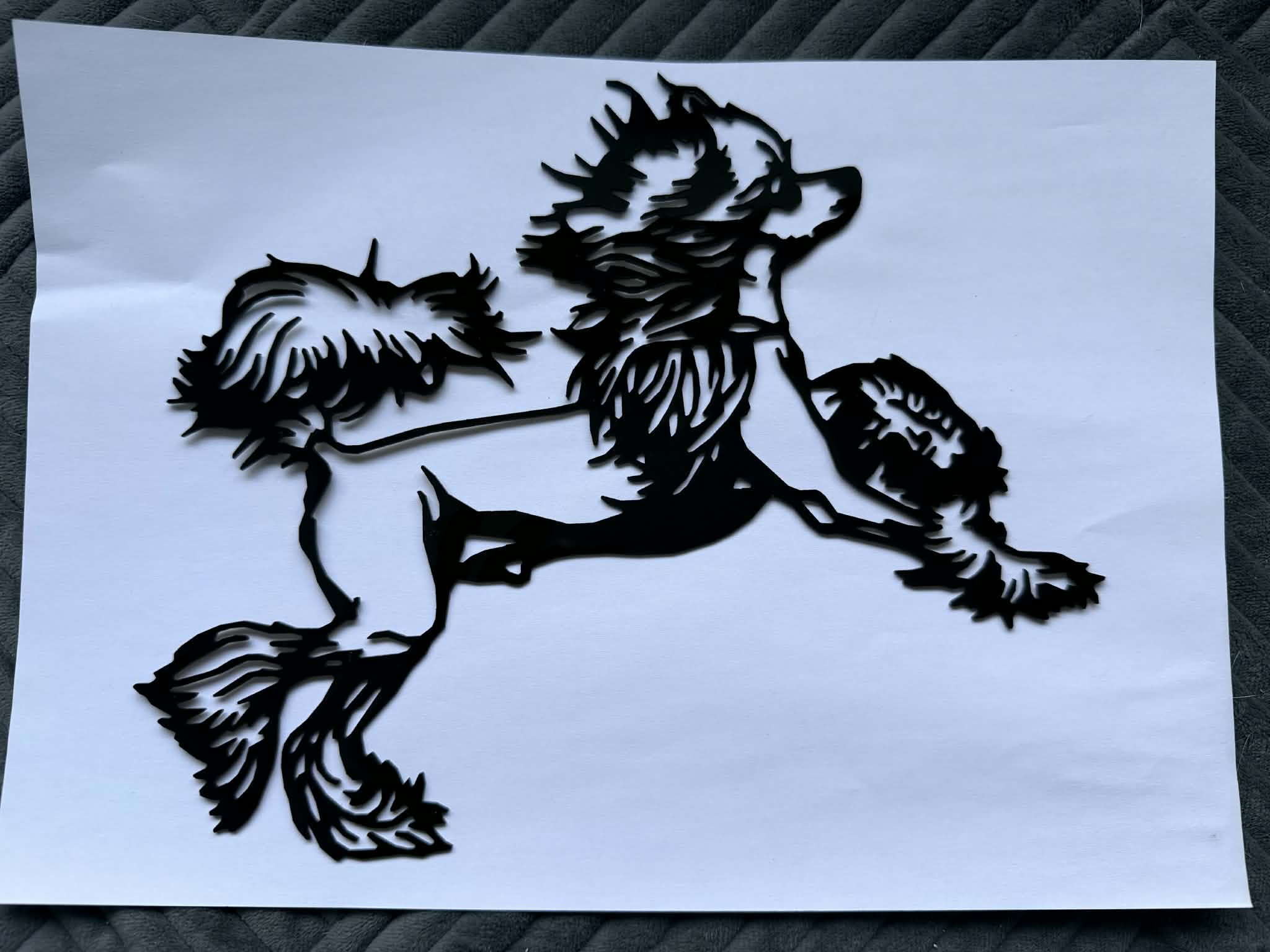 Black acrylic laser-cut piece of a poodle in mid-run